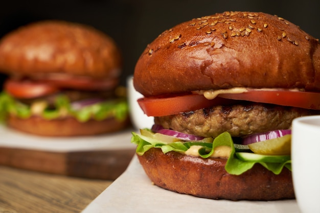 Aantal hamburgers met frietjes en ketchupsaus. Grote hamburgers en frietjes op houten tafel achtergrond. Fastfood achtergrond instellen. Restaurant hamburgermenu