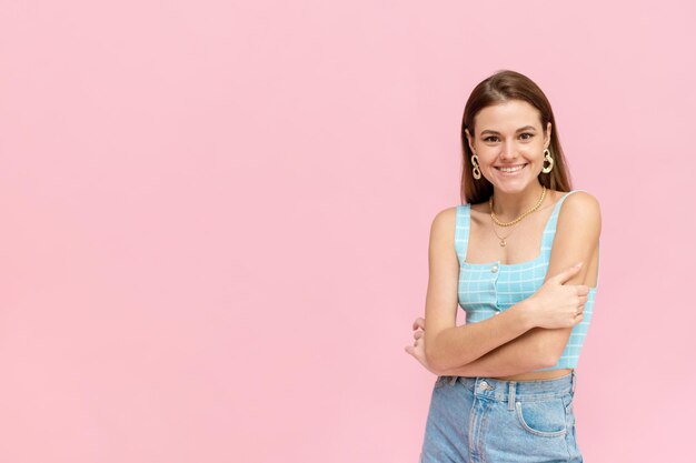 Aantrekkelijk donkerharig meisje in een lichte zomeroutfit glimlacht met kopieerruimte Positieve glimlachende vrouw die zich voordeed op roze achtergrond