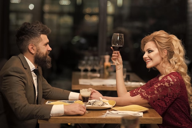 Aantrekkelijk elegant jong stel dat een wijn drinkt in het restaurant.