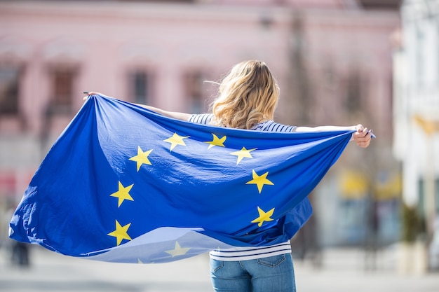 Aantrekkelijk gelukkig jong meisje met de vlag van de Europese Unie.