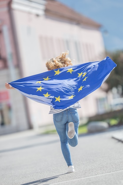 Aantrekkelijk gelukkig jong meisje met de vlag van de Europese Unie.