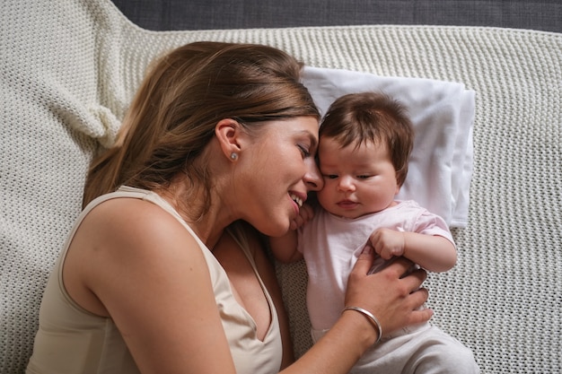 Aantrekkelijk gelukkig moederspel met kleine tenen babymeisjes. moeder zogende baby. oog in oog. gelukkig gezin. thuis. dol zijn op. lief hoor. tederheid.