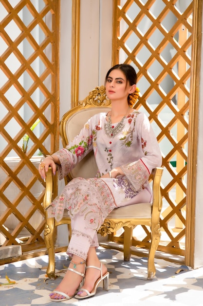 Aantrekkelijk jong meisje zittend op een stoel in traditionele kleding en sieraden voor mode fotoshoot
