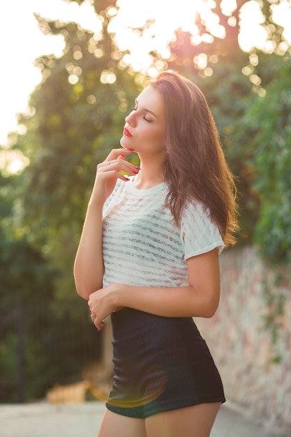 Aantrekkelijk jong model in stijlvolle kleding in het park bij zonsondergang