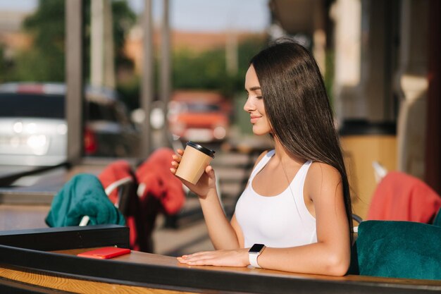 Aantrekkelijk meisje drinken koffie op het terras Mooie brunette rust tijdens een pauze