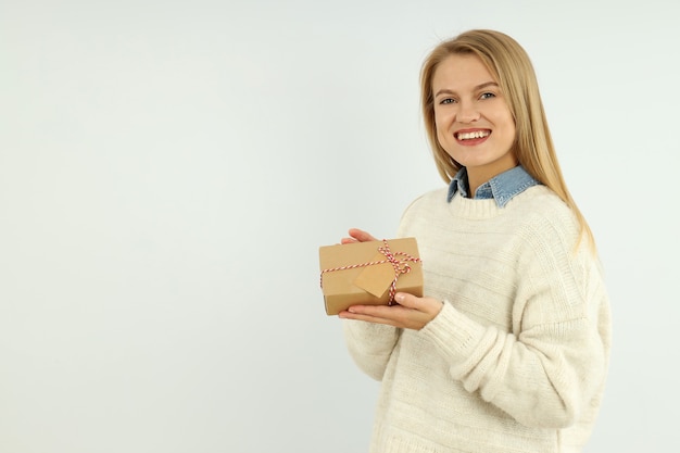 Aantrekkelijk meisje houdt geschenkdoos op witte achtergrond, ruimte voor tekst.