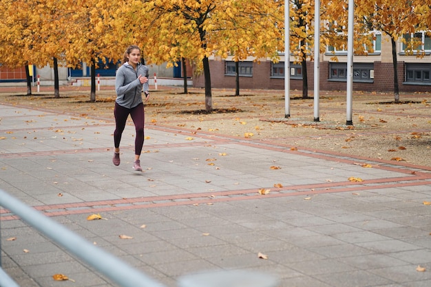 Aantrekkelijk meisje in sportieve kleding die door lege stadsstraten loopt