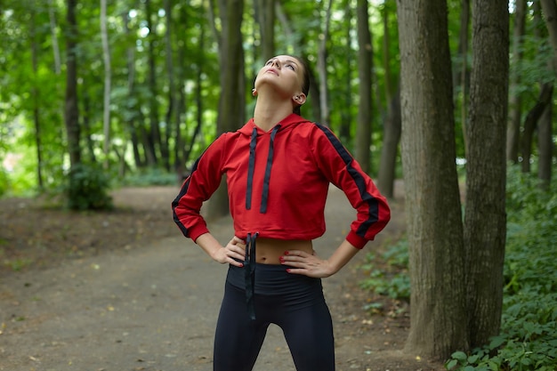 Aantrekkelijk meisje in sportkleding doet gymnastische oefeningen op de baan in het bospark.