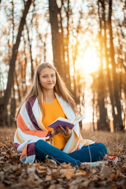 Aantrekkelijk meisje lezen van een boek in een herfst park