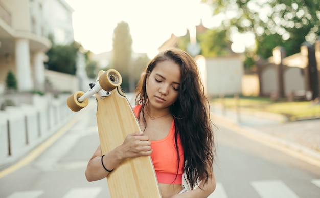 Aantrekkelijk meisje lopen met longboard in handen