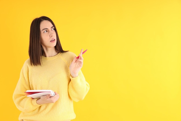 Aantrekkelijk meisje met notitieboekje op gele achtergrond