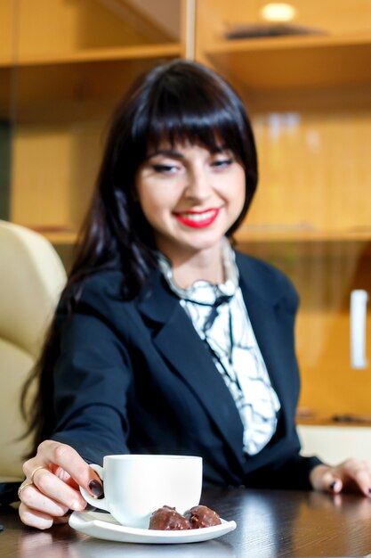 Aantrekkelijk meisje neemt een kopje koffie aan een tafel in het kantoor