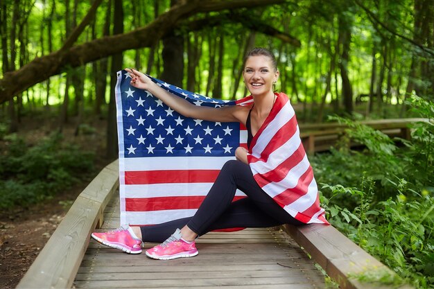 Aantrekkelijk meisje poseren met Amerikaanse vlag in bospark