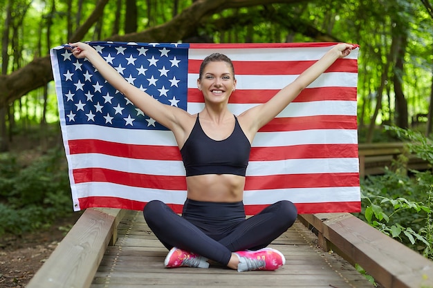 Aantrekkelijk meisje poseren met Amerikaanse vlag in bospark