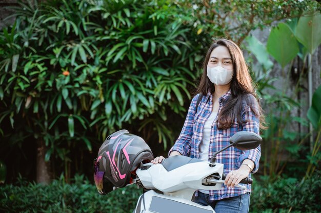 Aantrekkelijk meisje staande met masker naast motorfiets met helm met copyspace