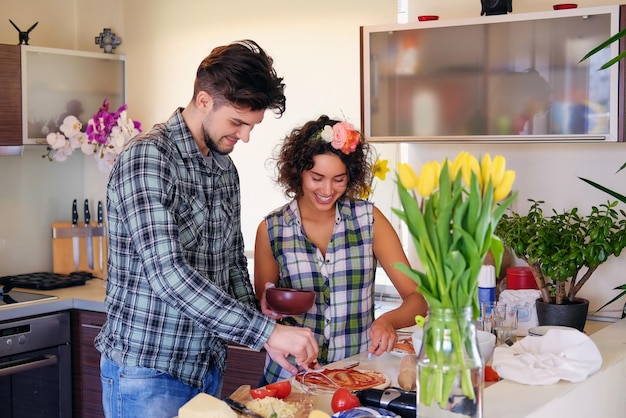 Aantrekkelijk paar brunette vrouw en een man in fleece shirt koken het eten in een huis familie keuken.