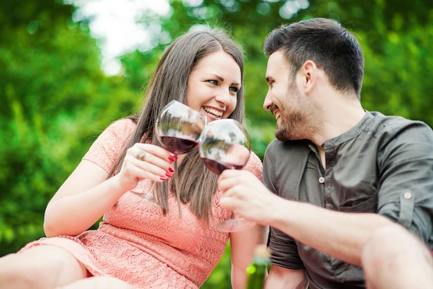 Aantrekkelijk paar dat op picknick rode wijn drinkt?