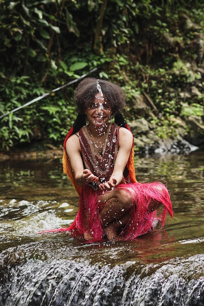 Aantrekkelijk Papoea-meisje van de dani-stam in traditionele kleding die water over het lachende gezicht spettert