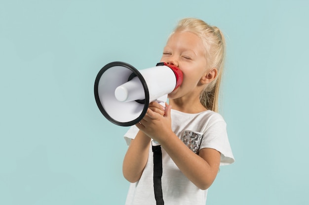 Aantrekkelijk schattig meisje in lichte kleding houdt megafoon