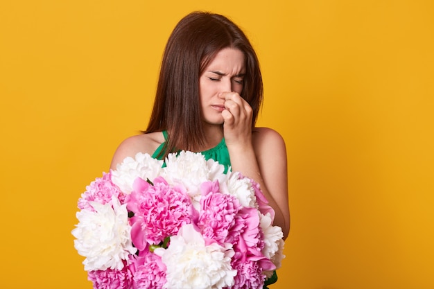 Aantrekkelijk slank schattig model met haar neus, sluitende ogen, kan de geur van pioenen niet verdragen, is allergisch voor bloemen en voelt zich niet lekker