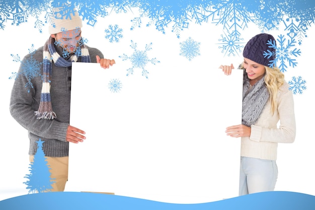 Foto aantrekkelijk stel in wintermode met poster tegen sneeuwvlokframe in blauw