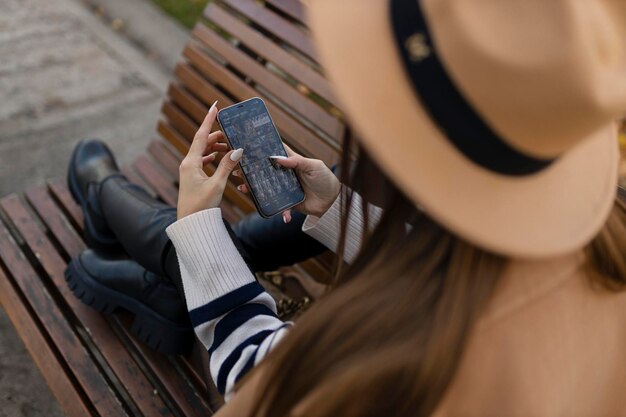 Aantrekkelijk vrolijk brunette meisje in trenchcoat met koffie om gelukkig mobiel buiten te gebruiken