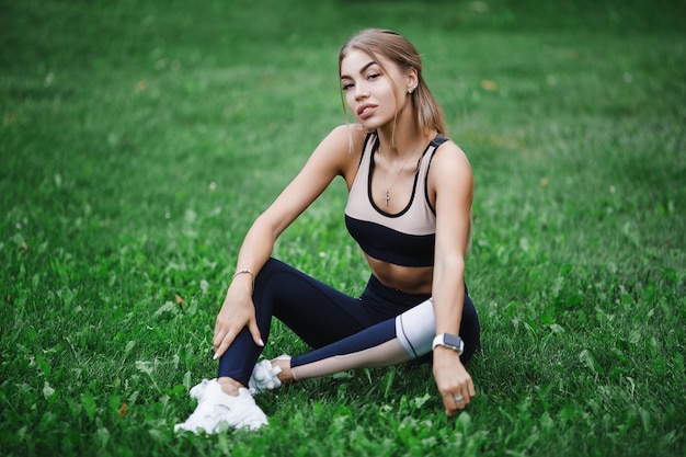 Aantrekkelijk wit Kaukasisch meisje in fitnesskleren die sport op groen gras doen