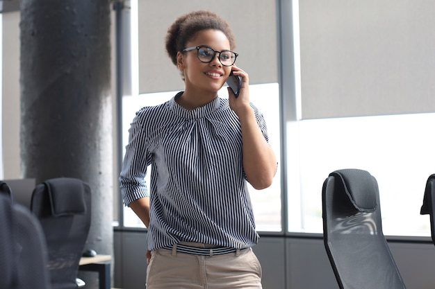 Aantrekkelijke Afro-Amerikaanse zakenvrouw praten met collega's op de mobiele telefoon.