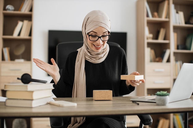 Aantrekkelijke arabische vrouw die met verraste gezichtsuitdrukking in document vakje kijkt