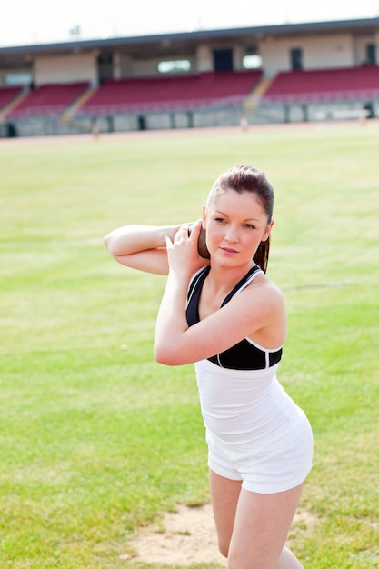 Aantrekkelijke atletische vrouw tijdens een kogelstoten training in een stadion