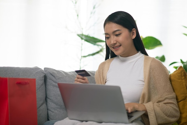 Aantrekkelijke Aziatische vrouw die online winkelt Gebruik smartphone-laptop en creditcard voor betaling