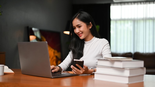 Aantrekkelijke aziatische vrouw die op internet surft met een laptop in haar woonkamer