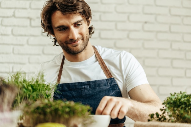 Aantrekkelijke bebaarde man boer zorgt voor spruiten van microgreens