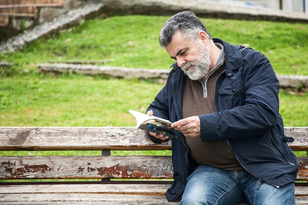 Aantrekkelijke bebaarde man lezen in een park