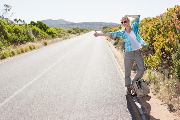 Aantrekkelijke blonde hapering die op landelijke weg wandelen