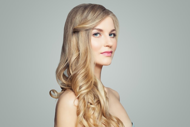 Aantrekkelijke blonde vrouw met een gezonde huid en krullend haar Gezichtsbehandeling haarverzorging en cosmetologie concept