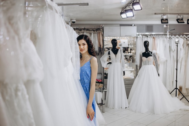 Aantrekkelijke bruid die een trouwjurk kiest in de winkel