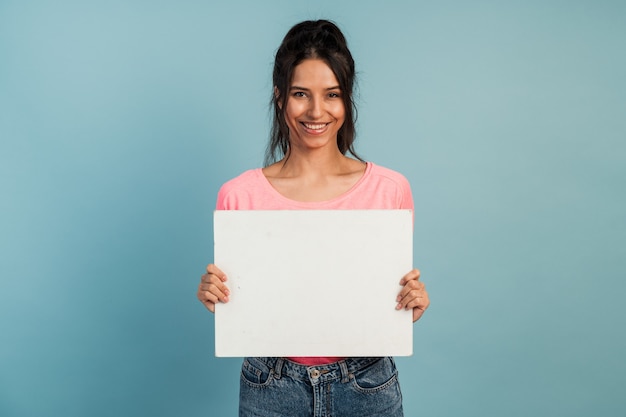 Aantrekkelijke brunette houdt in haar handen een blanco vel papier