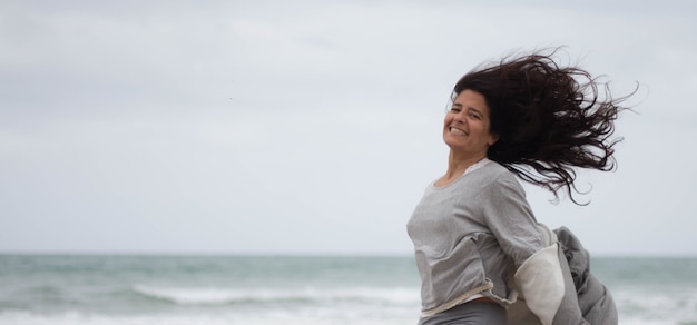 Aantrekkelijke brunette Spaanse vrouw met lang haar in een positieve, vrolijke houding en lachend