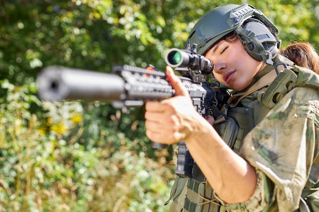 Aantrekkelijke dappere militaire vrouw met een pistool in het bos, overleven in het wilde bos