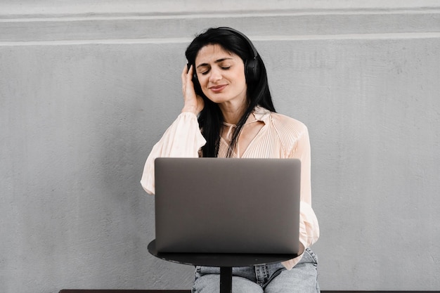 Aantrekkelijke dj-vrouw met laptop en koptelefoon die muziek mixt en nieuwe compositie luistert Aanbiddelijk Georgisch meisje geniet van haar leven met muziek luisteren en chatten met vrienden