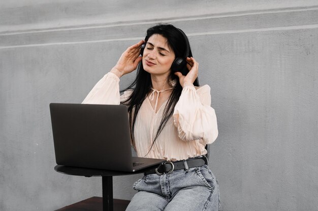 Aantrekkelijke dj-vrouw met laptop en koptelefoon die muziek mixt en nieuwe compositie luistert Aanbiddelijk Georgisch meisje geniet van haar leven met muziek luisteren en chatten met vrienden