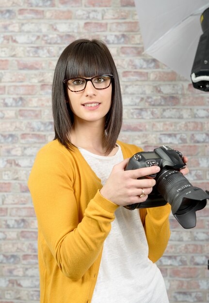 Aantrekkelijke donkerbruine vrouw met fotocamera in studio