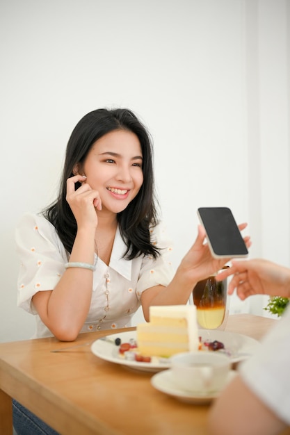 Aantrekkelijke duizendjarige Aziatische vrouw praat graag met haar beste vrienden terwijl ze ontspant in het café