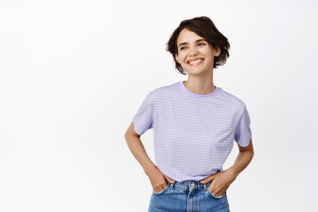 Aantrekkelijke en gelukkige brunette vrouw, glimlachend witte tanden, ontspannen hand in hand in jeans, studio