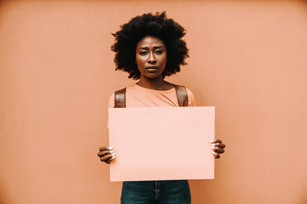 Aantrekkelijke ernstige Afrikaanse vrouw permanent en met blanco papier.