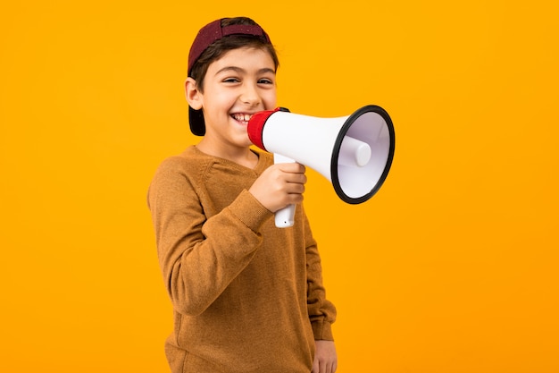 Aantrekkelijke Europese jongen met een megafoon in zijn handen voor een poster over een oranje studio