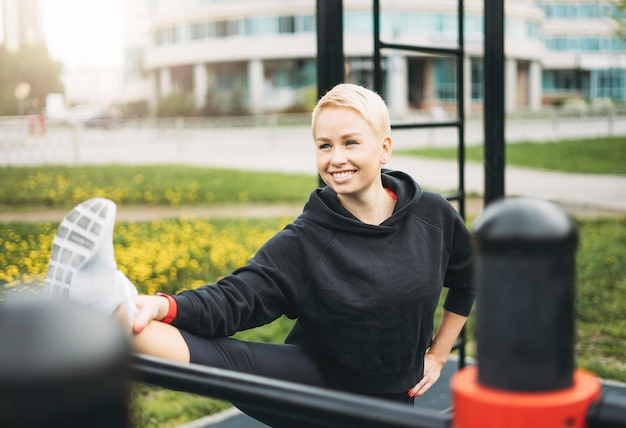 Aantrekkelijke fit jonge vrouw in sportkleding die zich uitstrekt op straat training gebied. Gezonde levensstijl in de stad