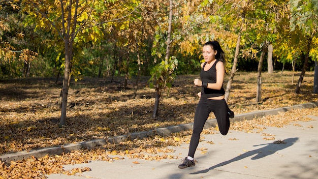 Aantrekkelijke fit vrouw atleet loopt op snelheid langs een landelijke laan door een park