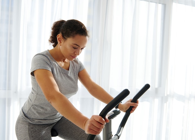 Aantrekkelijke fit vrouw uitoefenen op een hometrainer thuis op een mooie zonnige dag